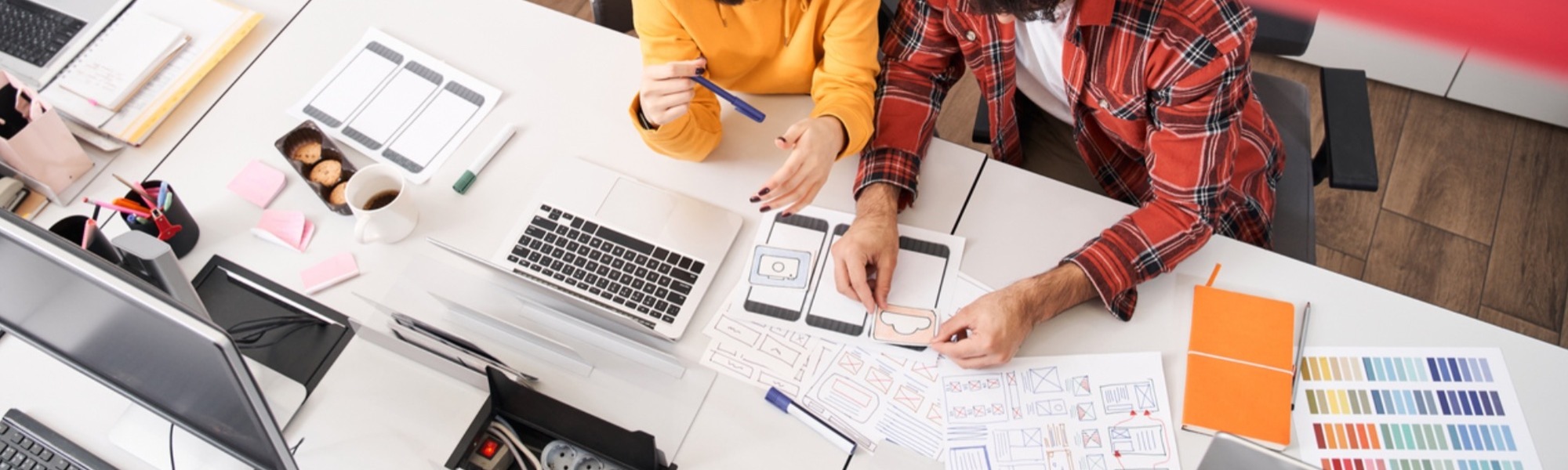 Creative designers working on desk with laptop and iPhone cutouts